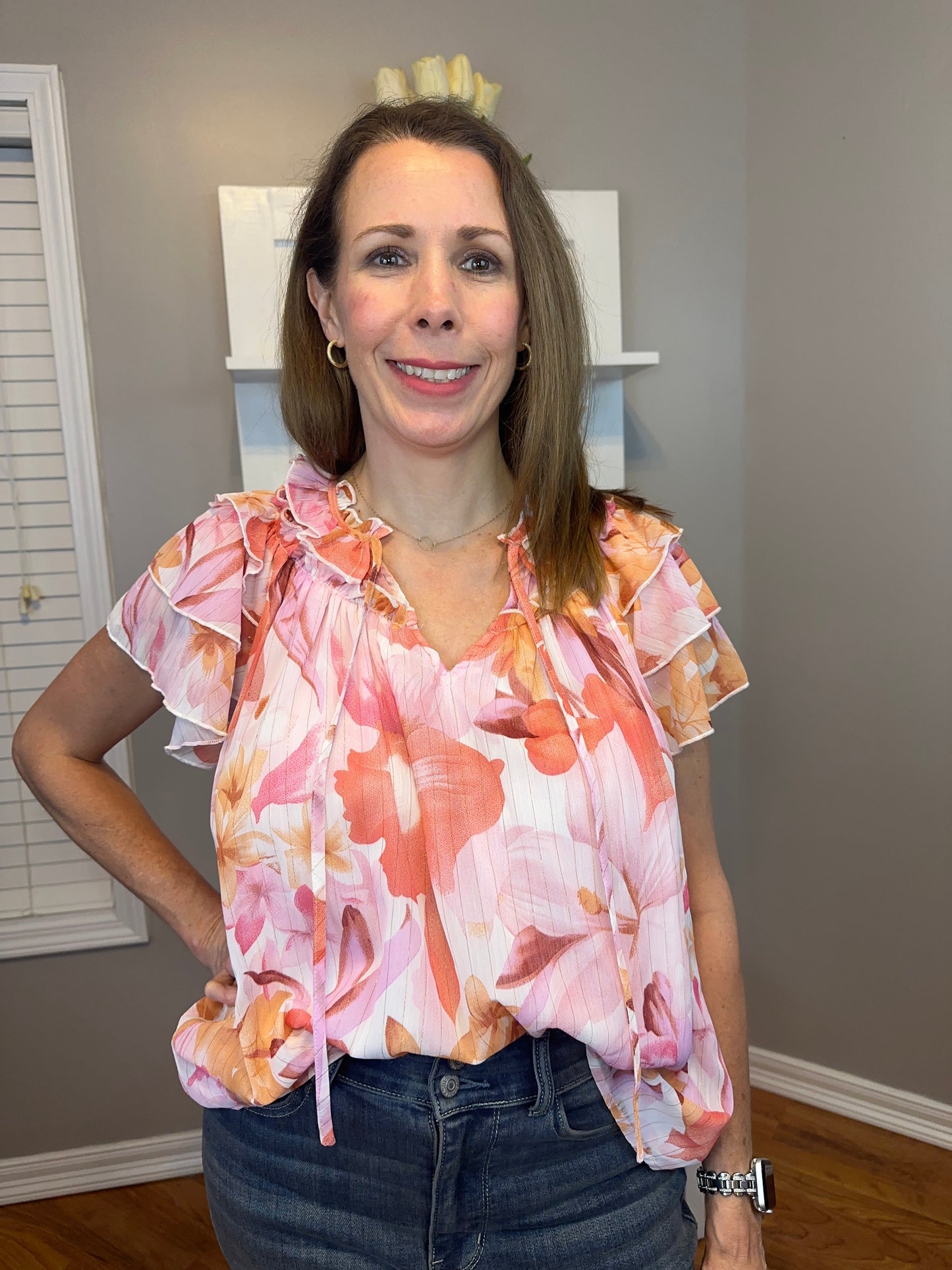 Floral print v-neck ruffle sleeve top featuring self tie at front neck.