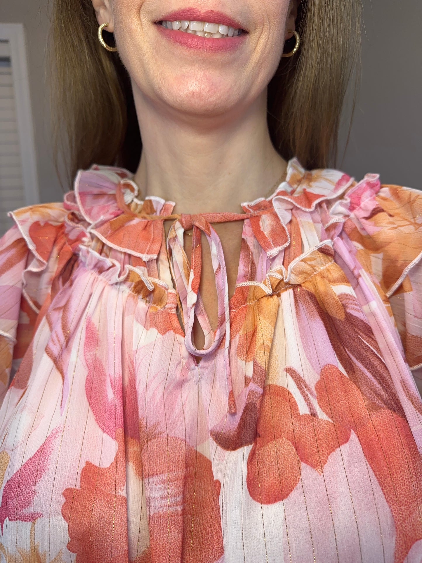 Floral print v-neck ruffle sleeve top featuring self tie at front neck.