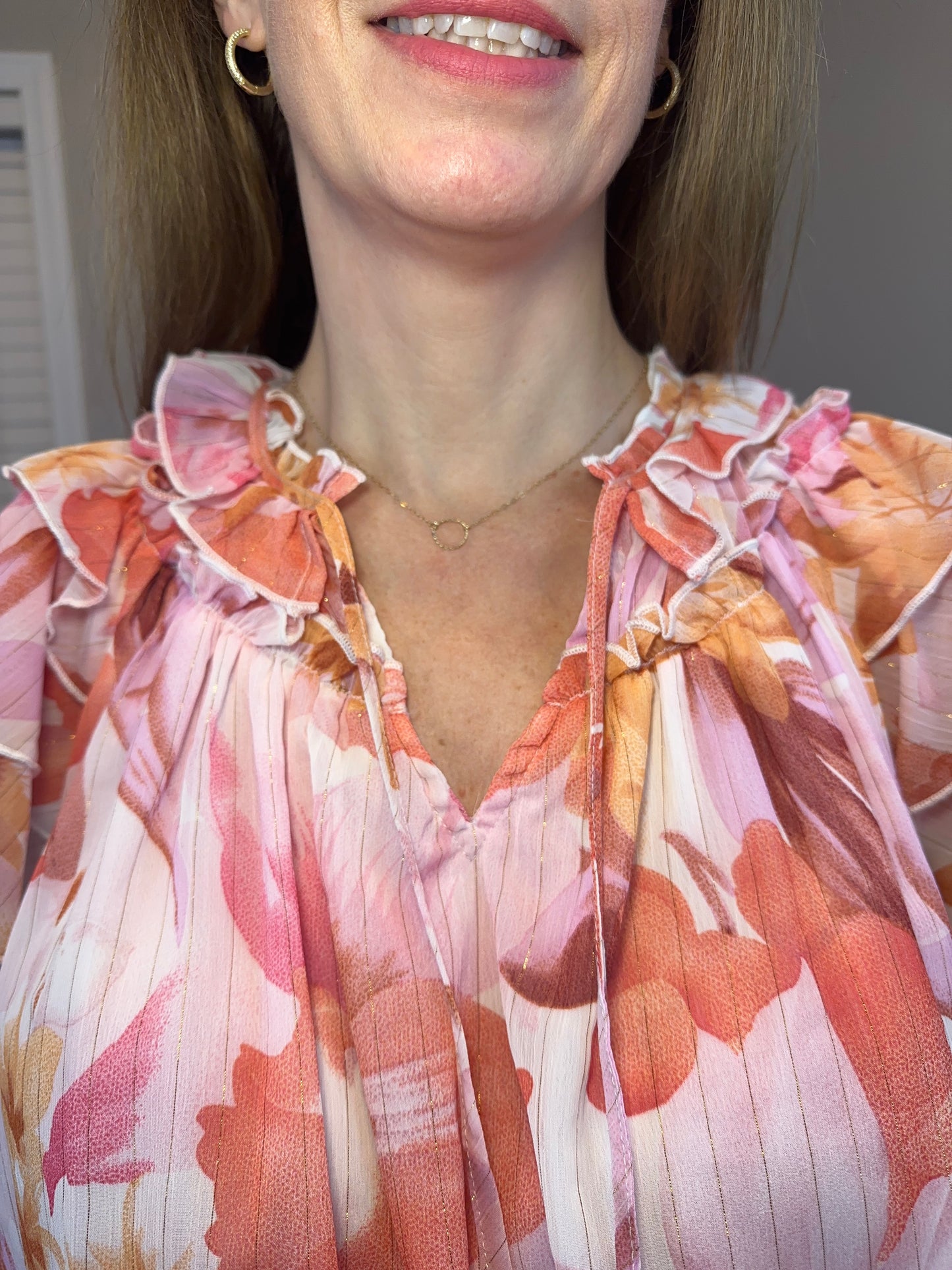 Floral print v-neck ruffle sleeve top featuring self tie at front neck.