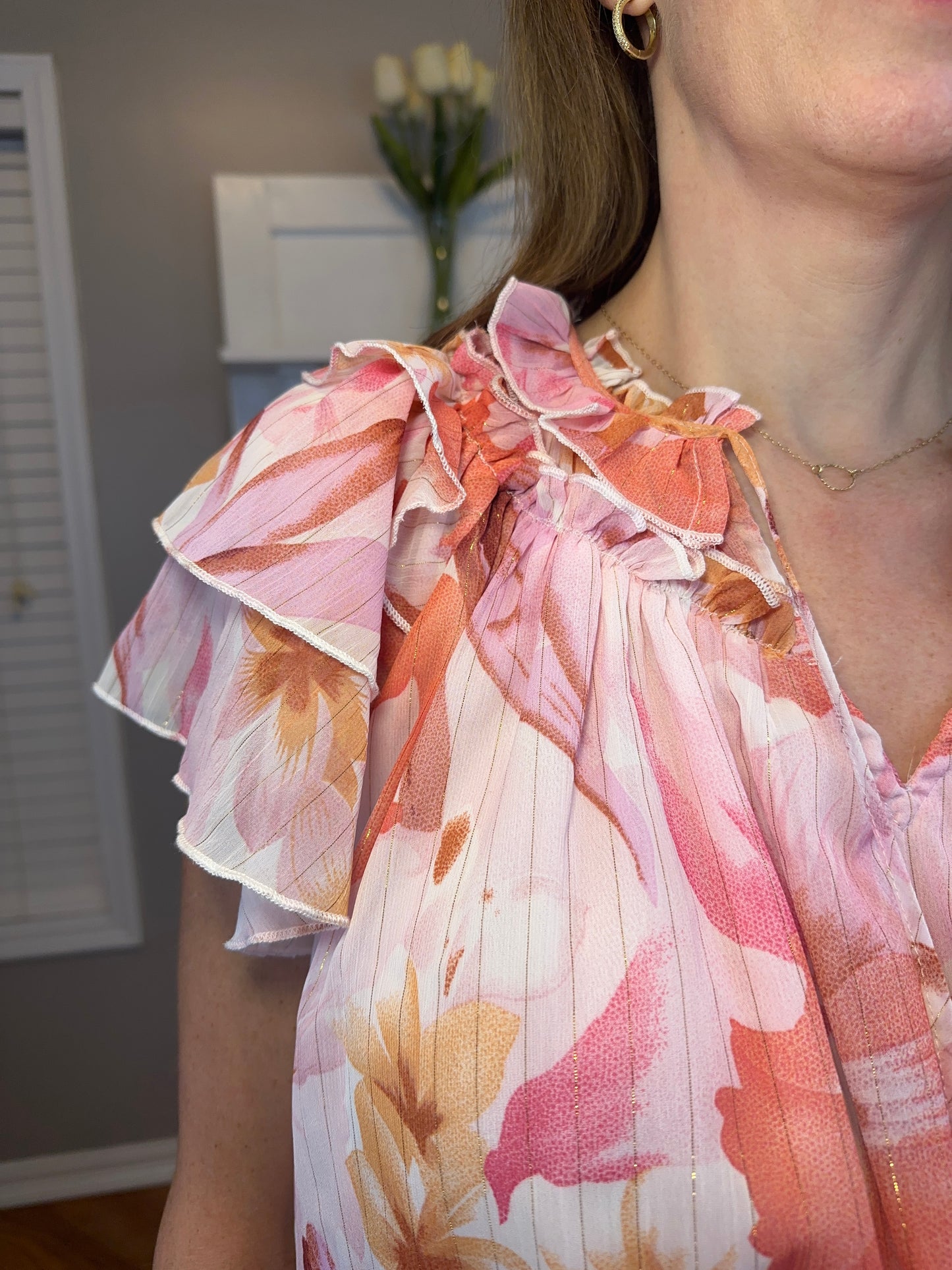 Floral print v-neck ruffle sleeve top featuring self tie at front neck.