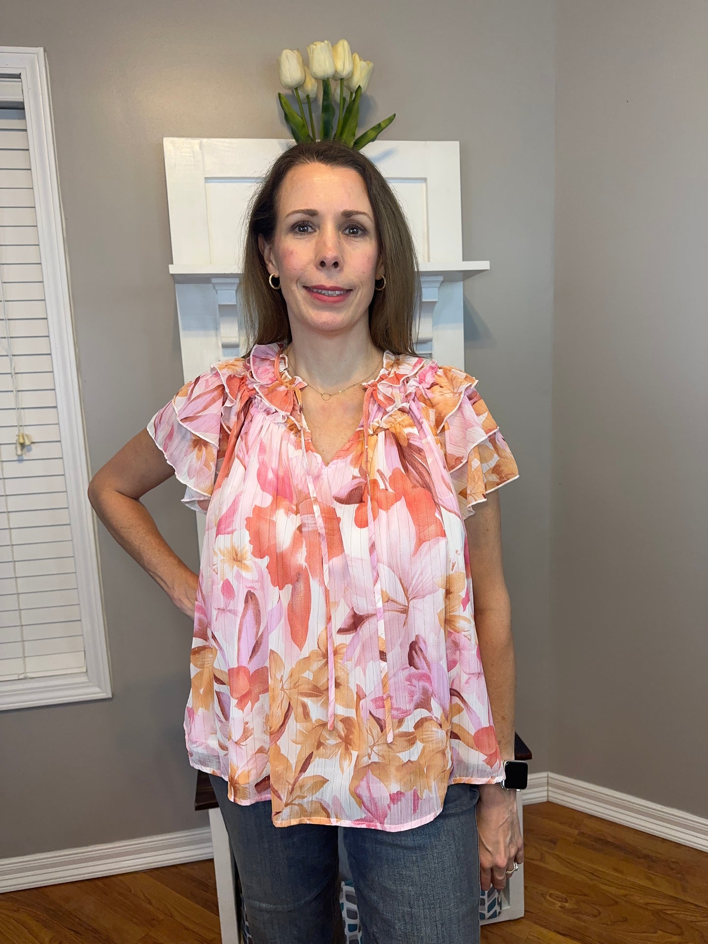 Floral print v-neck ruffle sleeve top featuring self tie at front neck.