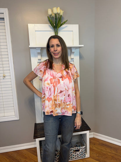 Floral print v-neck ruffle sleeve top featuring self tie at front neck.