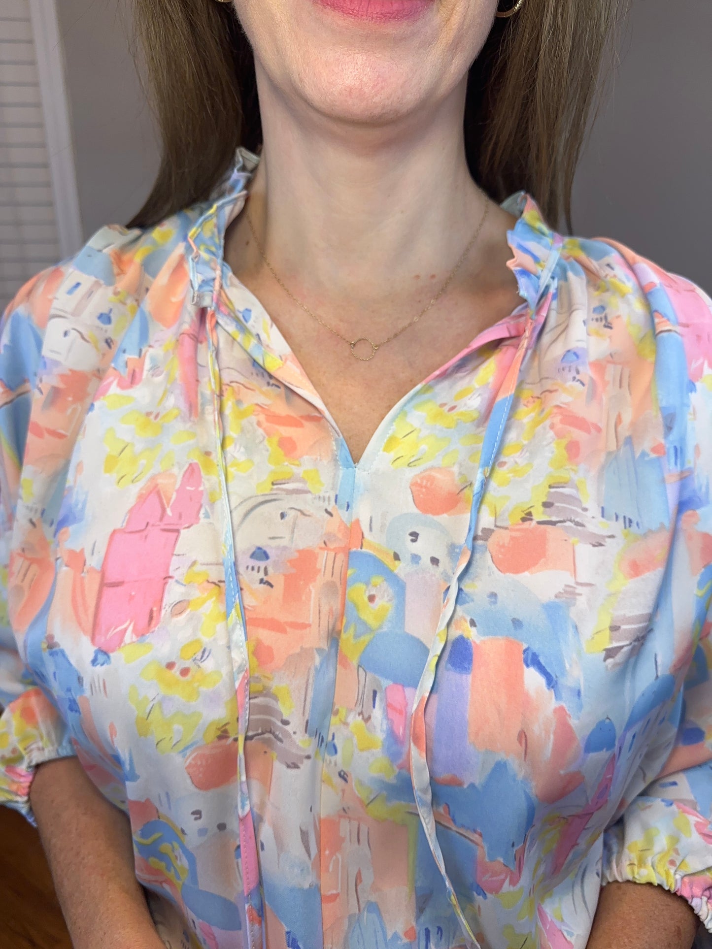 Pink multi printed v-neck 3/4 sleeve top featuring ruffle detail at neck.