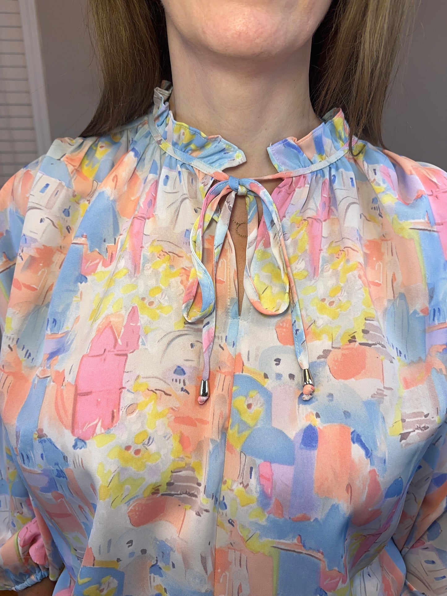 Pink multi printed v-neck 3/4 sleeve top featuring ruffle detail at neck.