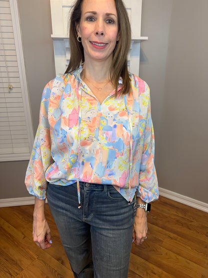 Pink multi printed v-neck 3/4 sleeve top featuring ruffle detail at neck.